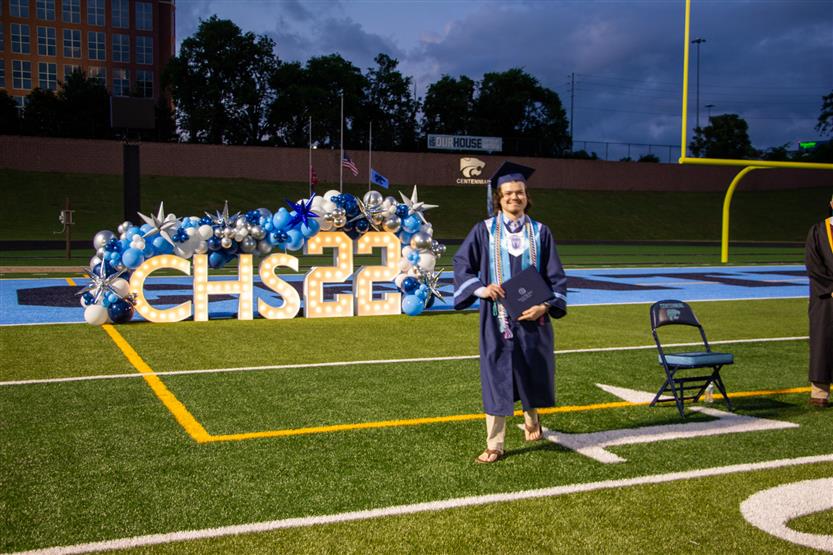 Students graduate outside on a football field